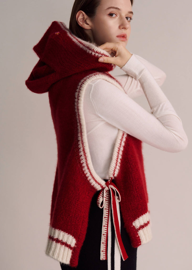 Person wearing a red and white hooded vest on a plain background
